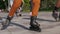 Close-up legs of teenagers. Riding roller skating down the street.