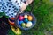 Close-up of legs of toddler girl with colorful stockings and shoes and basket with colored eggs. Child having fun with