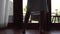 Close-up of legs of woman in bathrobe unveil curtain, standing near the window in home.