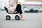 Close-up of the legs of a woman sitting on a baby car that is standing on the pavement