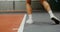 Close-up of the legs of a young male tennis player bouncing while serving ball