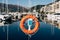 A close-up of a lifebuoy on a stand on the dock overlooking the mountains and yachts on the water. Marina for yachts in