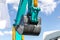 Close-up of lifted bucket of Sunward excavator against the background of the cloudy sky. Construction equipment fair