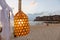 Close up of light bulb on the wire. Glow up In the lamp. Hanging on the beach against the background of tourists who sit on a