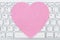 Close-up of a light gray computer keyboard with a pink heart