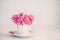 Close up light pink peony flowers bouquet in a decorative cup and saucer on white wooden table. Love background. Gift greeting