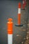 A close up line of orange and white traffic bollards.