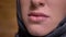 Close-up lip-portrait in profile of muslim woman in hijab smiling into camera on bricken wall background.
