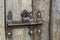 Close-up of lit by sun old rough made of wooden planks house door or barn gate with iron rusty slide bolt lock. Outdated