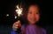 Close up little Asian girl playing fire sparklers in the dark at night