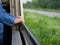 Close up of little baby`s hands holding on a frame of an opened window on a traveling train