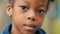 Close-up little beautiful afro girl in park schoolgirl seriously looking at camera. Portrait of brown eyes african