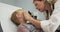 Close up of little boy getting eye exam at pediatric office from female doctor