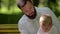 Close-up of little boy with his dad are trying on a bow tie They are sitting on a park bench.