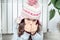 Close up little brunette girl face breathing on hands to keep warm near cold broken heating radiator, looking at camera