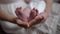 Close-up little Caucasian infant feet in hand of unrecognizable woman indoors. Newborn baby child with caring loving