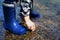 CLOSE UP OF LITTLE CHILD WEARING BLUE RAINBOOTS AND PLAYING WITH