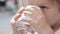 Close-up of a little cute girl drinking pure water from a glass