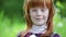 Close up little ginger girl\'s face smiling in the park