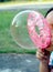 close up little girl blowing large soap bubbles in playground