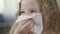 Close-up of little girl blowing and wiping her nose with a napkin, rheum