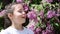 Close-up of the little girl enjoys the smell of violet flowers in the park.