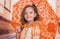 Close up of little girl wearing a beautiful colonial costume and holding an orange umbrella in a blurred background