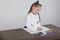 Close up of little girl in white blouse which is focused on drawing. Preschooler is learning how to draw. Kindergarten and school.