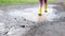 Close-up of little toddler girl wearing yellow rain boots and walking and running during sleet on rainy day. Cute child in colorfu