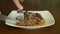 Close up locked shot of steak. Hands with knife and fork take part of meat steak from plate.