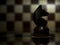 Close-up of a lone black horse on a chessboard