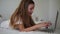 Close up of long haired beautiful european girl typing on laptop. Smiling little girl with interest watch laptop and lay