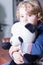 Close-up of lovely blond boy with curly hair hugging panda toy