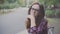 Close up of lovely middle-aged woman with glasses sitting on park bench smiling at camera.