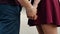 Close-up of lovers hands. Couple in love are standing holding hands. Both are in dark red clothes. Slow mo