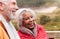 Close Up Of Loving Active Senior Couple Resting By Gate As They Walk Along Coastal Path In Winter