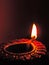 Close up low key diwali oil clay lamp,chirag or panti on a dark orange black background with bright orange red light illu