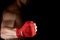 Close up low key portrait of an aggressive muscular fighter, showing his fist on dark background, selective focus