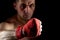 Close up low key portrait of an aggressive muscular fighter, showing his fist on dark background, selective focus