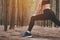 Close up of lower body of woman doing yoga and stretching legs before running in forest at outdoors. Sports and Nature concept.