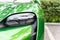 Close-up luxury shiny green sportscar supercar vehicle matrix LED system headlight lamp detail parked on city street outdoors.