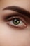 Close-up macro beautiful female eye with perfect shape eyebrows. Clean skin, fashion natural smoky make-up. Good vision