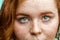 Close up macro face of young red ginger freckled woman with beautiful green eyes