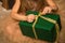 Close up, macro. Hands of a little girl in a golden dress tied / untied the ribbon on a gift box in a green package. Christmas