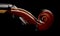 Close up macro of scroll on brown wooden fiddle or violin, classic musical instrument, over black background