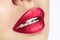 Close-up macro shot of female mouth. Glamour red lips Makeup with sensuality gesture. Magenta gloss lipstick