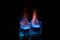 Close up, macro. Two glass glasses with blue alcohol with a flame of burning fire. Black background. Copy space