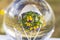 Close up macro view of  crystal ball with  inverted image of hanging basket  with yellow purple pansies.