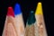 A close up macro view of a group of four child`s colouring pencil, with green in the foreground