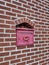 Close up of a mailbox cemented into a red brick wall in downtown Georgetown